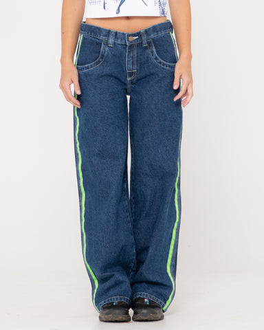 Woman wearing Reflekt Loose Low Rise Denim Jean in Deep Sea Blue / Lime