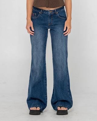 Woman wearing Shorty Freida Flare Low Rise Jeans in Blasted Deep Sea Blue