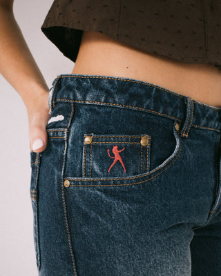 Woman wearing Shorty Freida Flare Low Rise Jeans in Blasted Deep Sea Blue