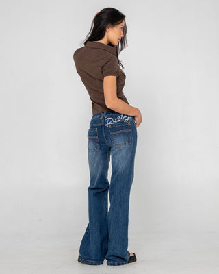 Woman wearing Shorty Freida Flare Low Rise Jeans in Blasted Deep Sea Blue