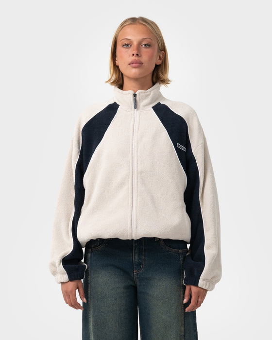 woman-wearing-two-tides-zip-through-sherpa-fleece-in-egret-navy-blue