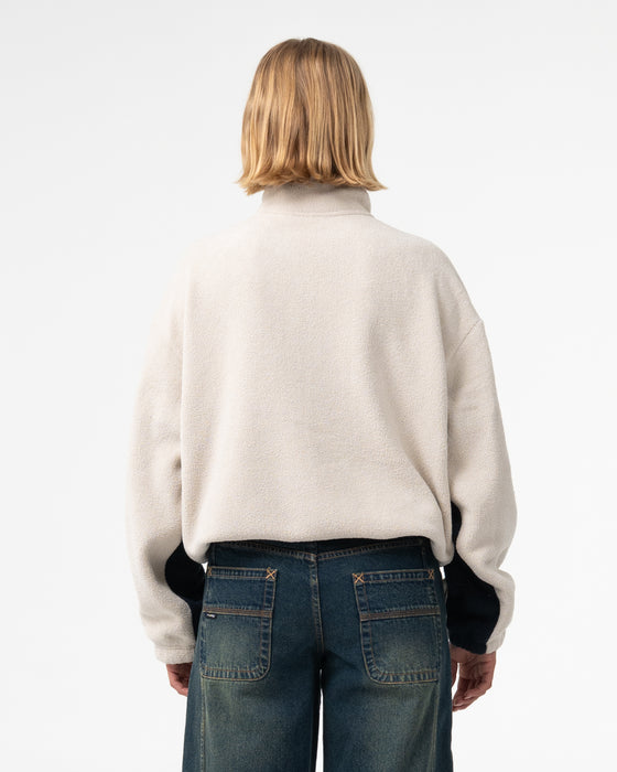 woman-wearing-two-tides-zip-through-sherpa-fleece-in-egret-navy-blue