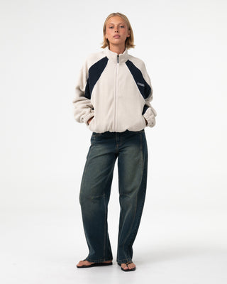 Woman wearing Two Tides Zip Through Sherpa Fleece in Egret / Navy Blue
