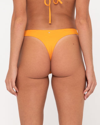 Woman wearing Sandalwood Brazilian Bikini Pant in Bright Tangerine