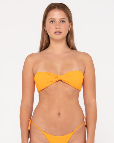 Woman wearing Sandalwood Twist Bandeau Bikini Top in Bright Tangerine