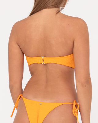 Woman wearing Sandalwood Twist Bandeau Bikini Top in Bright Tangerine