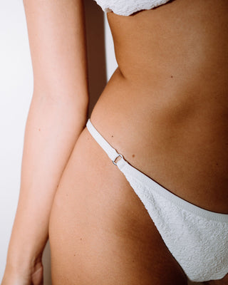 Woman wearing Sandalwood Ring Cheeky Bikini Bottom in Bright White