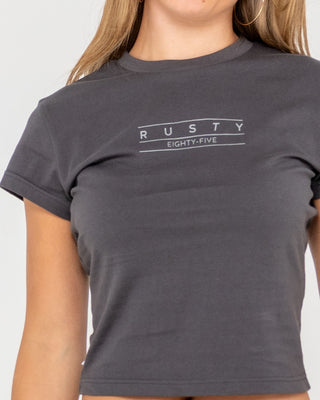 Woman wearing Rusty Essentials Skimmer Baby Tee in Carbon