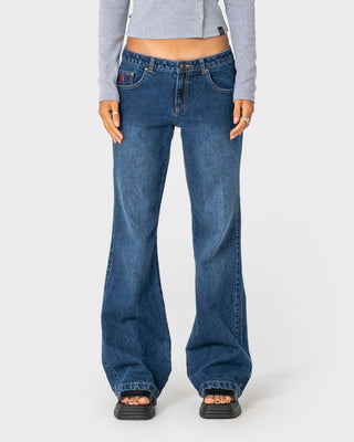 Woman wearing Shorty Freida Flare Low Rise Jeans in Blasted Deep Sea Blue
