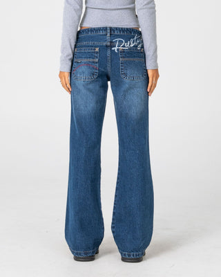 Woman wearing Shorty Freida Flare Low Rise Jeans in Blasted Deep Sea Blue