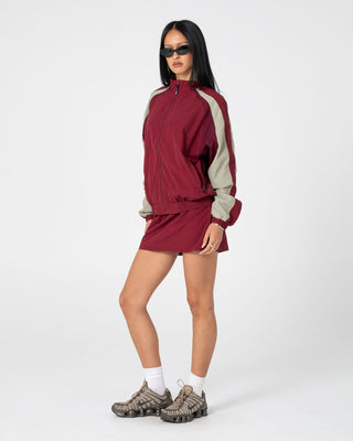 Woman wearing Breezy Wind Cheater Zip Through Jacket in Cranberry