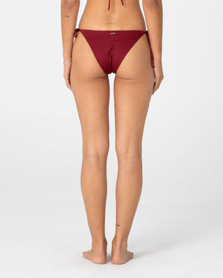 Woman wearing Cedar Midi Side Ties Bikini Bottom in Cranberry