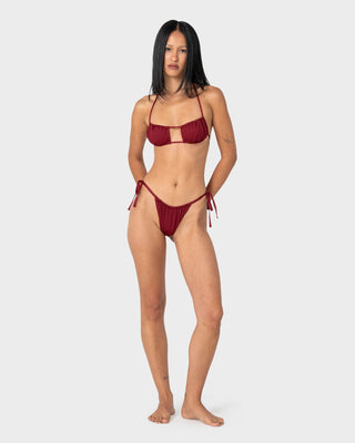 Woman wearing Cedar Cheeky Side Ties Bikini Bottom in Cranberry