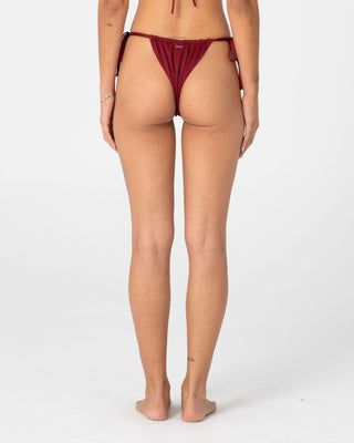 Woman wearing Cedar Cheeky Side Ties Bikini Bottom in Cranberry