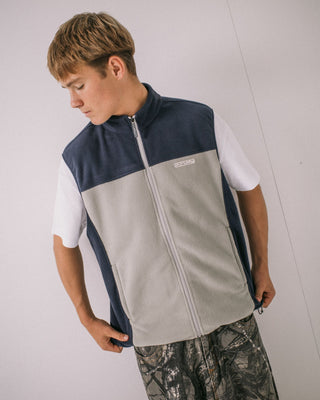 Man wearing On The Run Tech Fleece Vest in Stone Grey