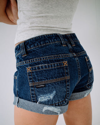 Woman wearing Pheonix Low Rise Denim Mini Short in Blasted Deep Sea Blue