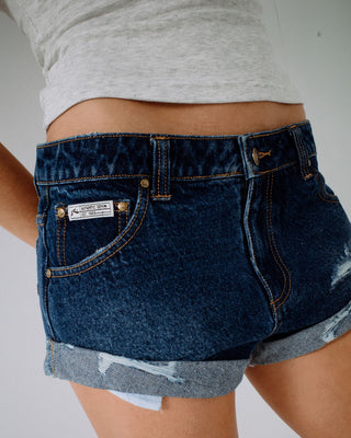 Woman wearing Pheonix Low Rise Denim Mini Short in Blasted Deep Sea Blue